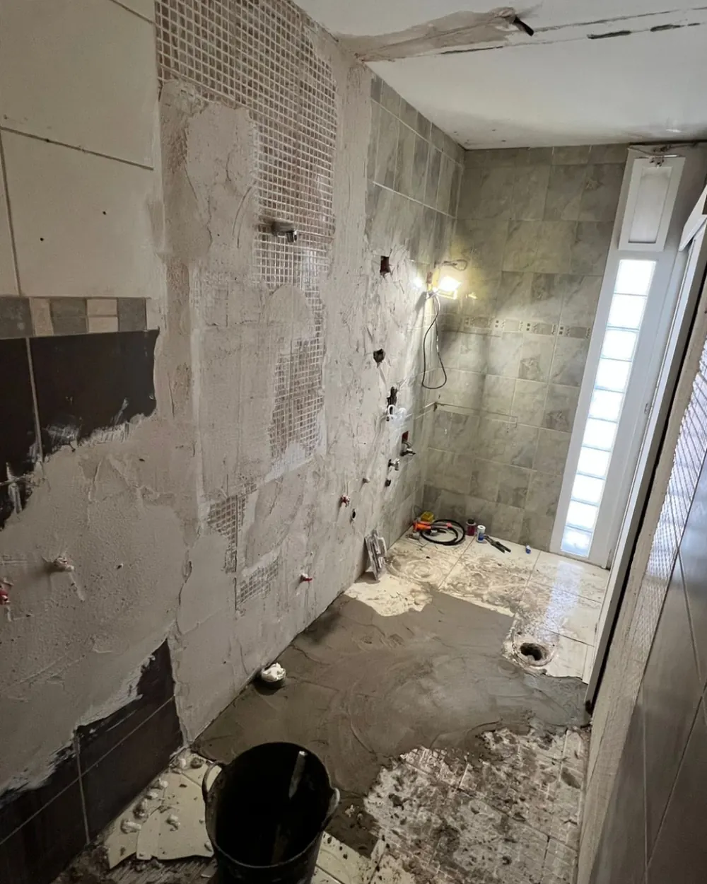 Pareti del bagno spicconate e nuovi impianti idraulici durante la demolizione