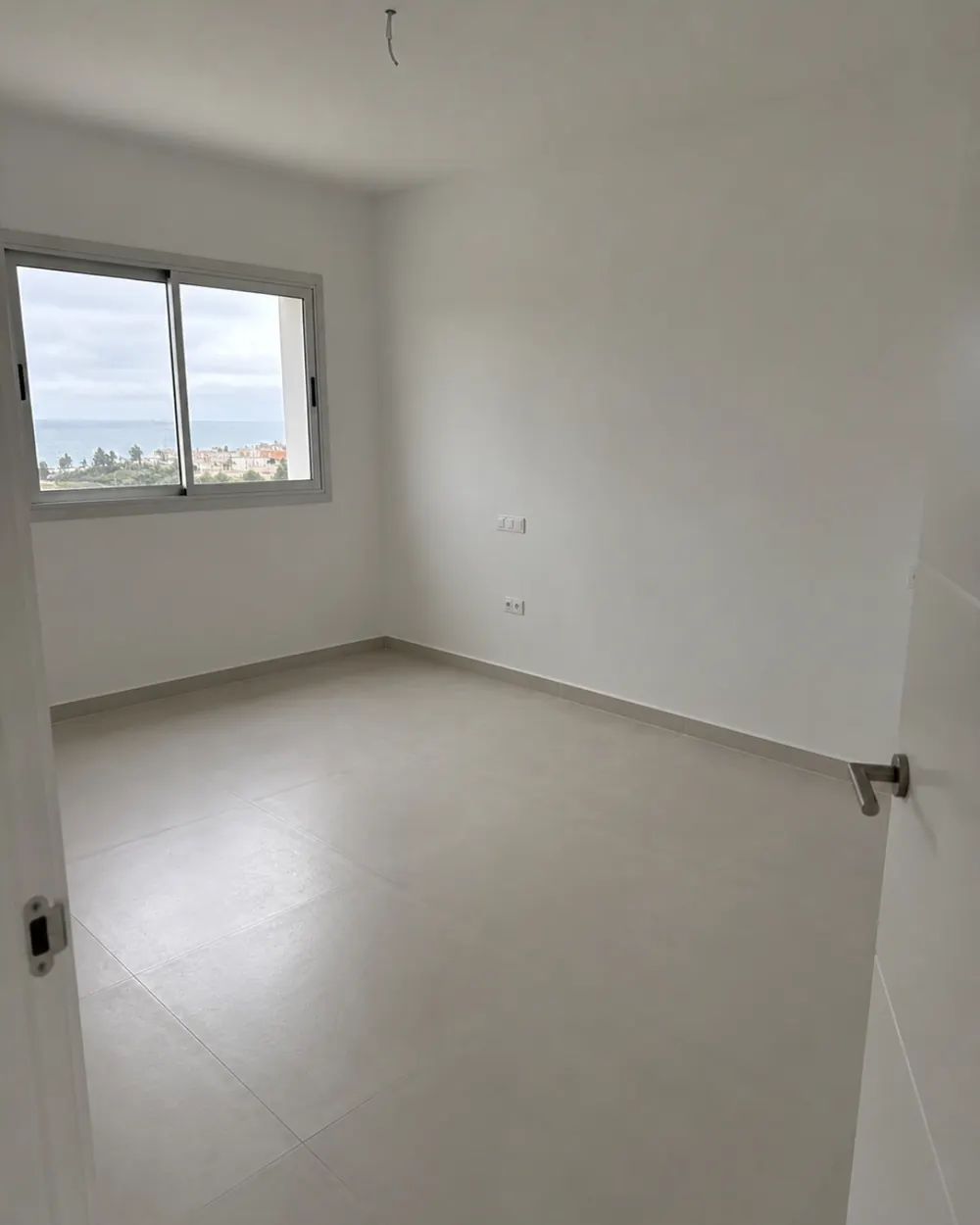Camera da letto con pavimento in gres di grande formato appena posato e vista mare