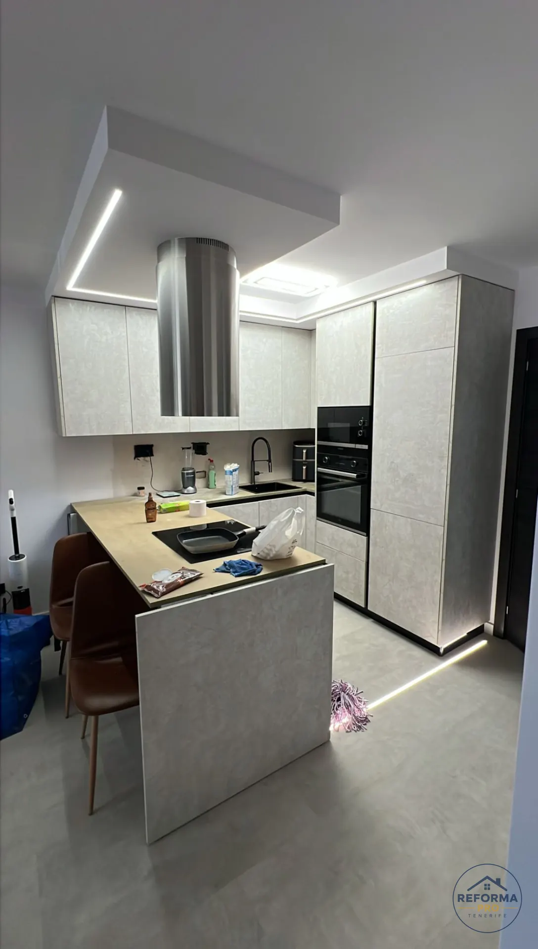 Cucina moderna finita con isola, cappa cilindrica e controsoffitto con luci LED