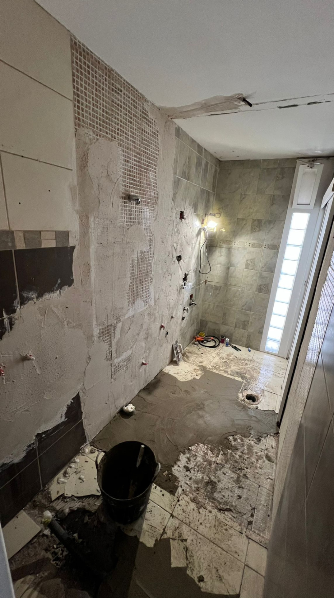 Pareti del bagno spicconate e nuovi impianti idraulici durante la demolizione