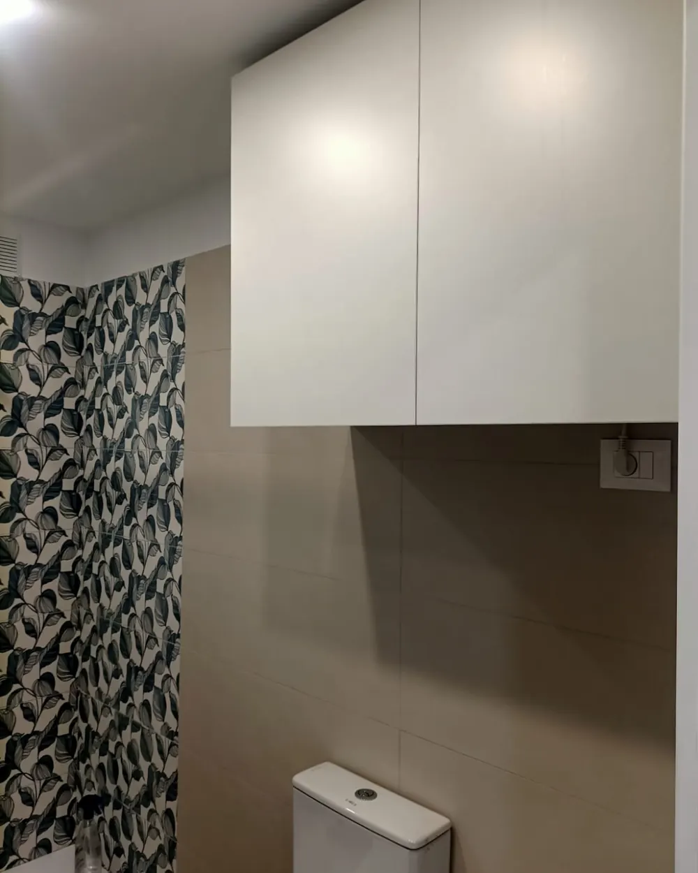 Pensile bianco su misura sopra il WC con rivestimento decorato nel bagno finito
