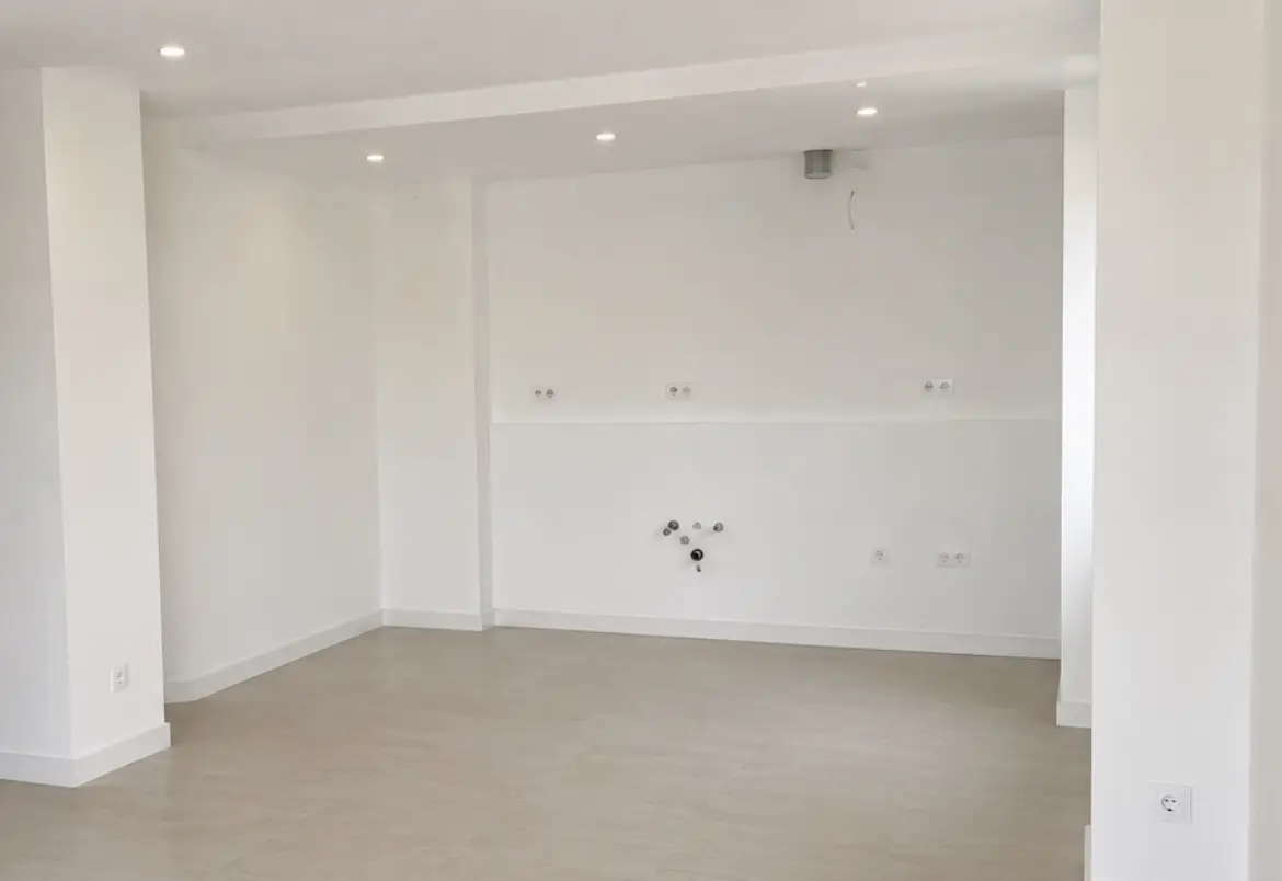 Ambiente ristrutturato con pavimento beige e predisposizioni per la cucina