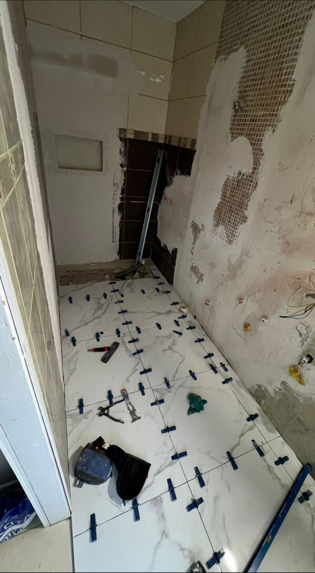 Posa del gres effetto marmo sul pavimento del bagno con distanziatori livellanti