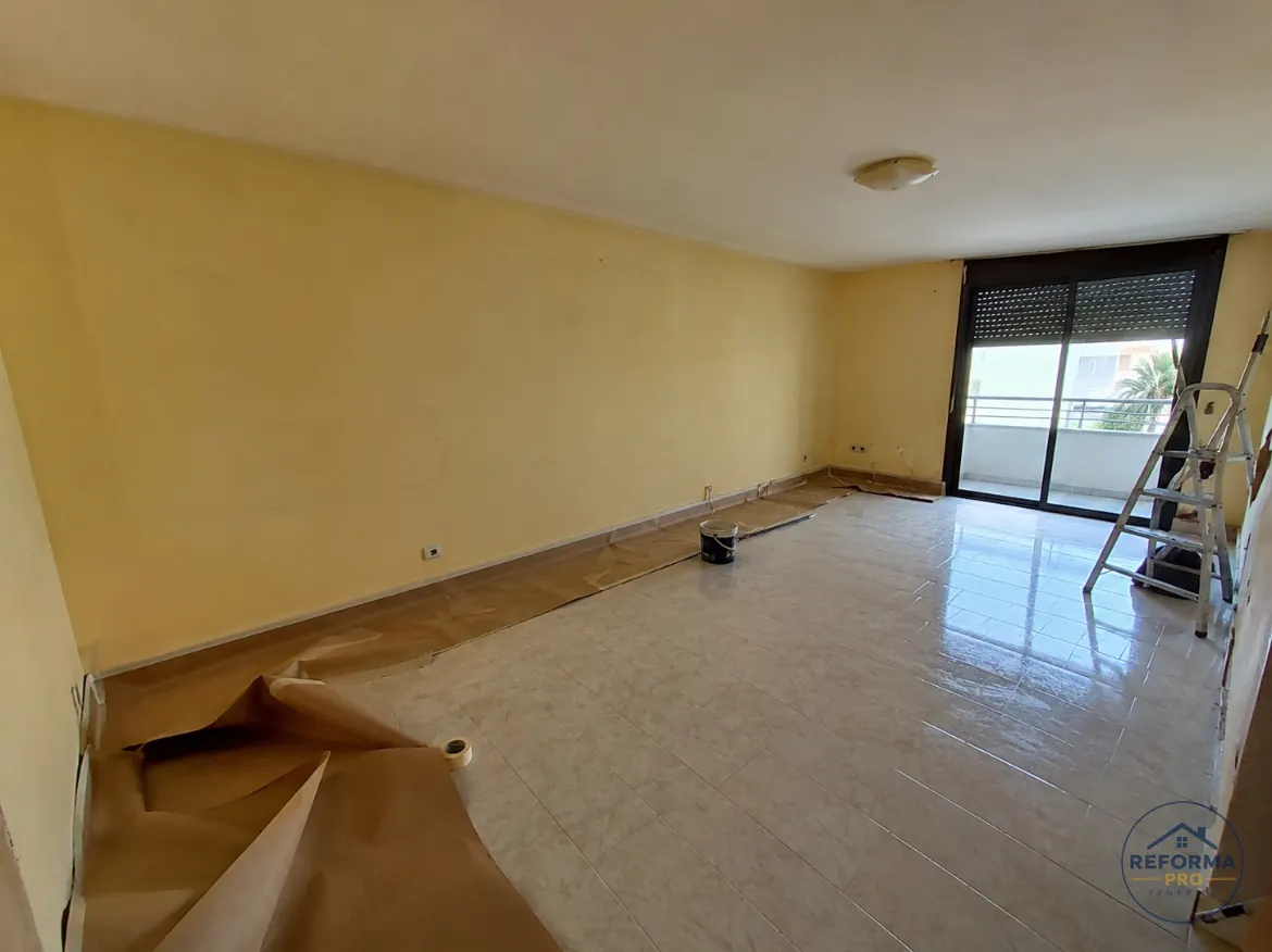 Salón con paredes amarillas antes de pintar, suelo protegido Salón con paredes amarillas antes de pintar, suelo protegido