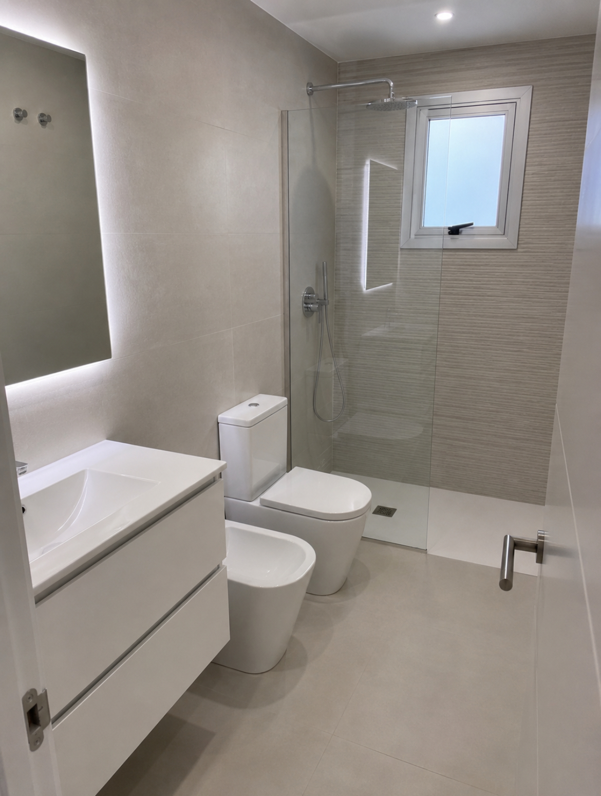 Bagno finito con doccia walk-in in vetro, sanitari sospesi e specchio retroilluminato Bagno finito con doccia walk-in in vetro, sanitari sospesi e specchio retroilluminato