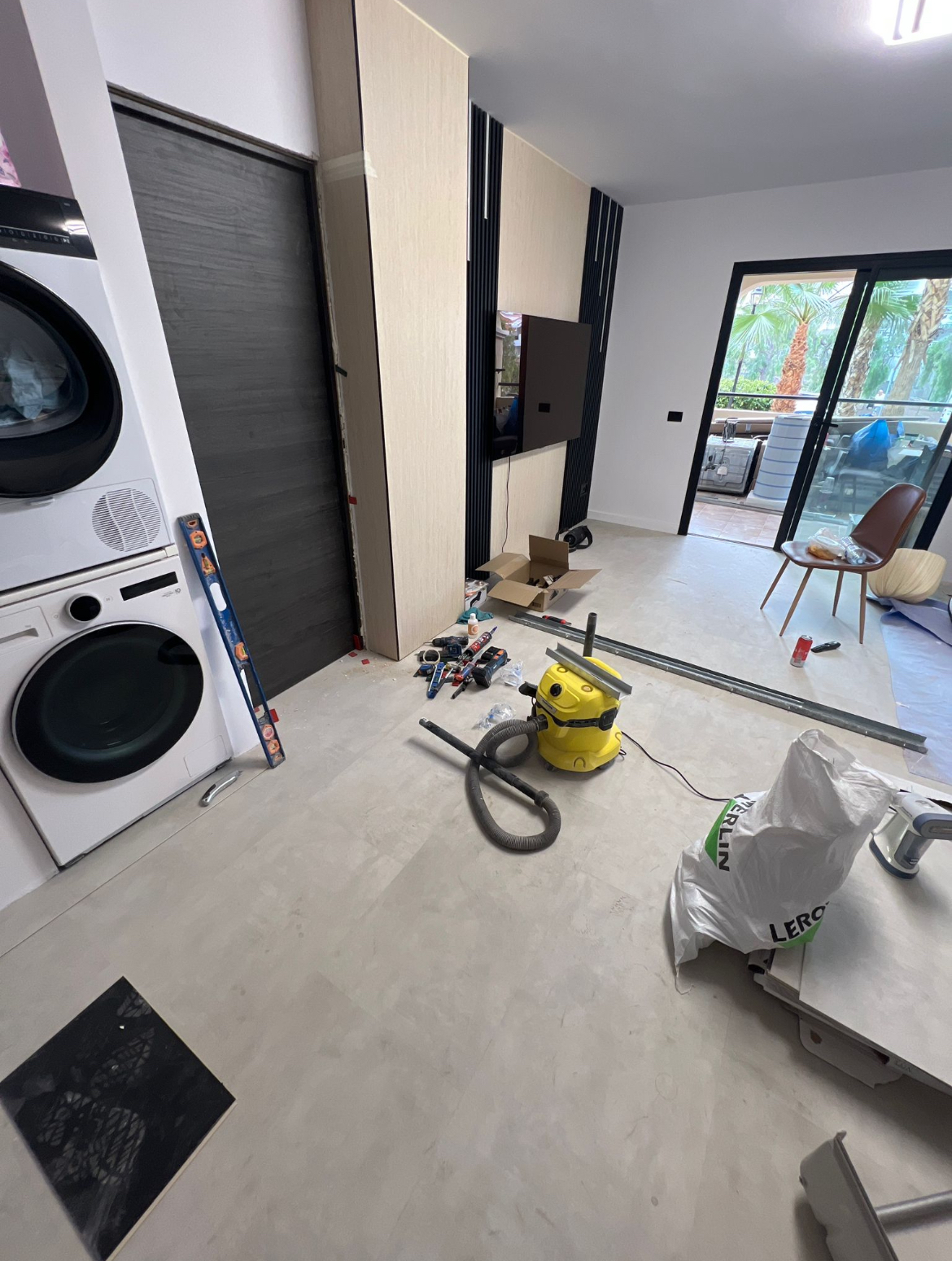 Cantiere in corso nel soggiorno con pannellatura TV in legno e microcemento a terra