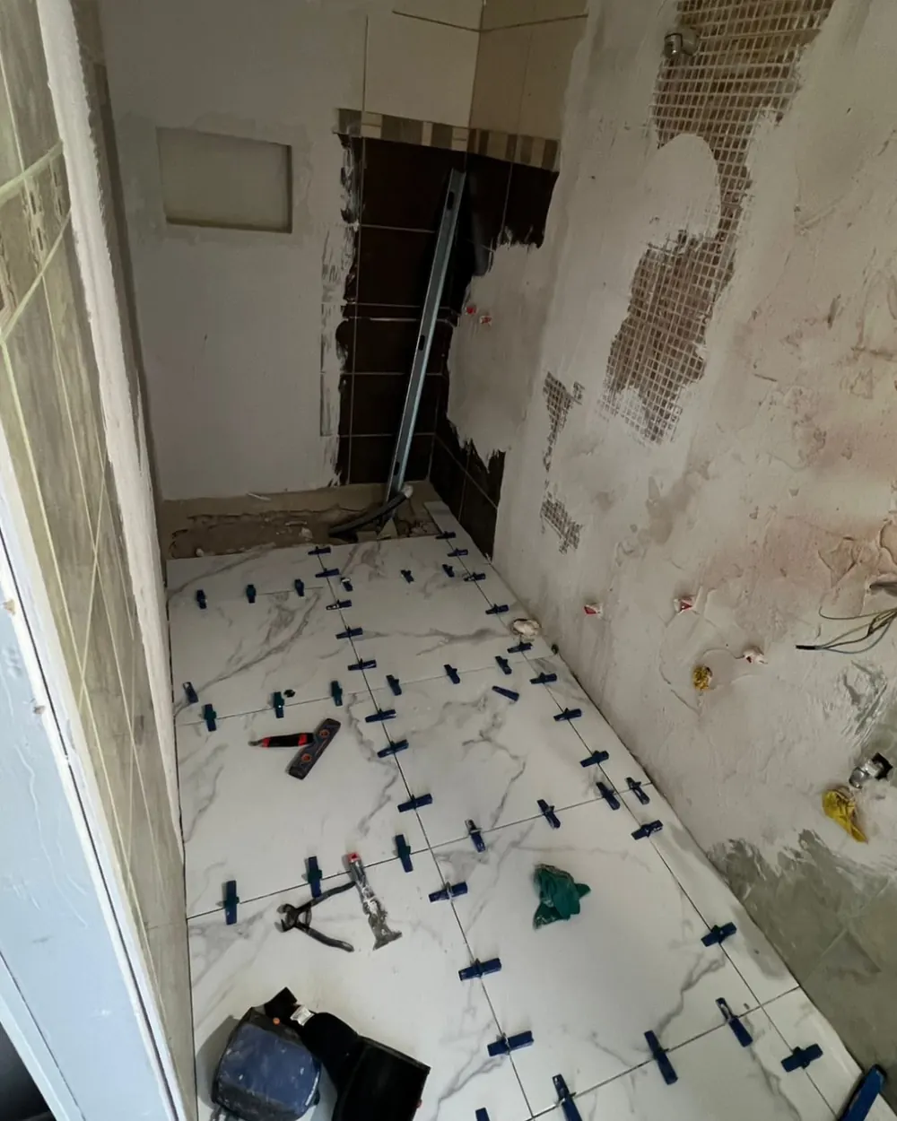 Posa del gres effetto marmo sul pavimento del bagno con distanziatori livellanti