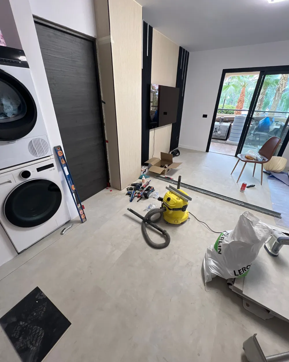 Cantiere in corso nel soggiorno con pannellatura TV in legno e microcemento a terra