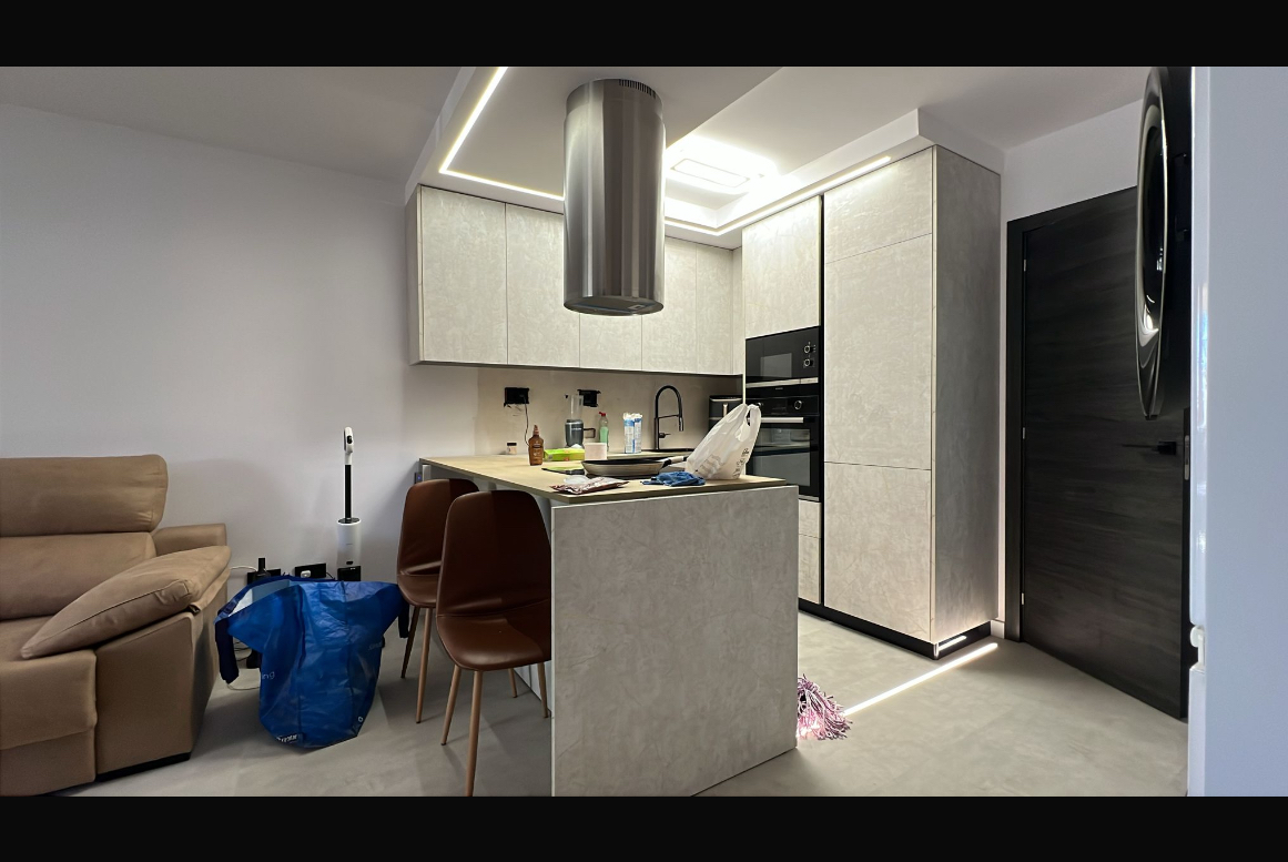 Zona giorno con cucina open space, controsoffitto illuminato e microcemento Zona giorno con cucina open space, controsoffitto illuminato e microcemento