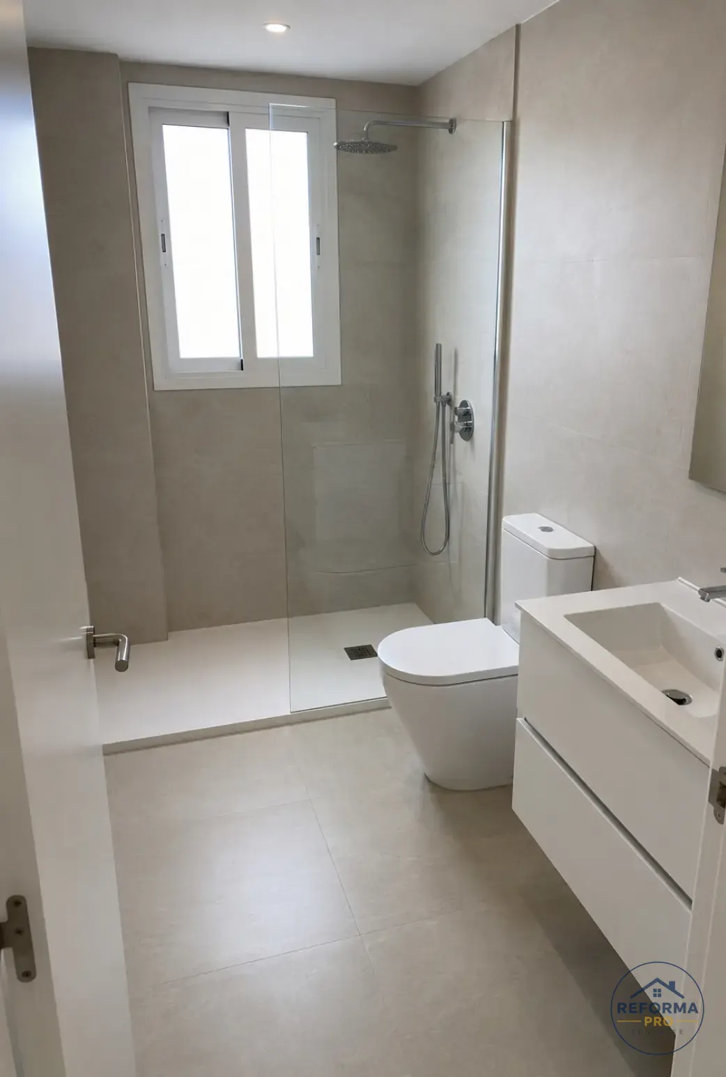 Bagno ristrutturato con doccia vetrata, rivestimento beige e mobile lavabo bianco