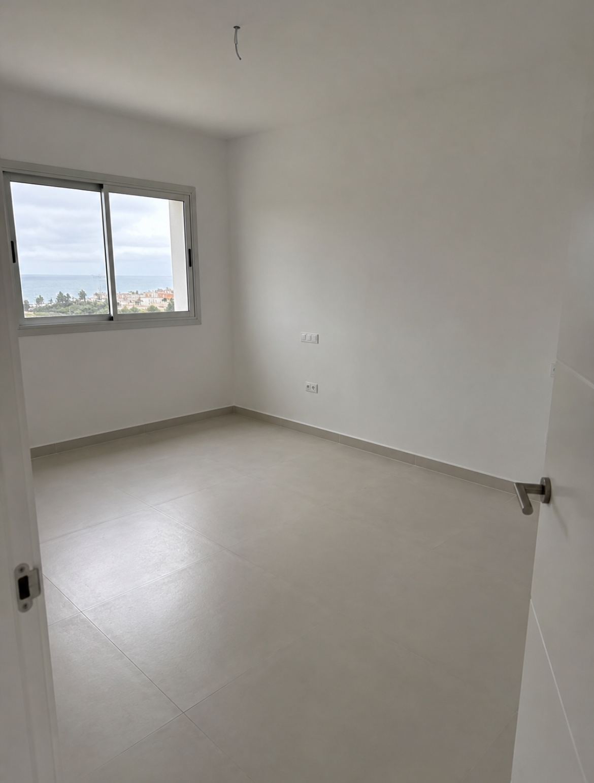 Camera da letto con pavimento in gres di grande formato appena posato e vista mare Camera da letto con pavimento in gres di grande formato appena posato e vista mare